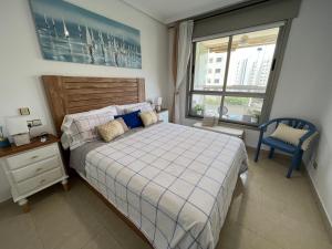 ein Schlafzimmer mit einem Bett und einem Stuhl und einem Fenster in der Unterkunft EDIFICIO CORUÑA CALA DE FINESTRAT. Luxury apt. in Benidorm + 82 Fotos