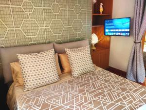 Schlafzimmer mit einem Bett mit Kissen und einem Flachbild-TV in der Unterkunft Vatican Heart Leone Apartment at Roman Terrace in Rom