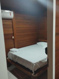 Cama pequeña en habitación pequeña con sábanas blancas en Pousada Rangel, en Santo Amaro