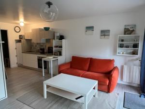 ein Wohnzimmer mit einem roten Sofa und einem weißen Tisch in der Unterkunft La Garrigue, au milieu des pins maritimes... in Cucq