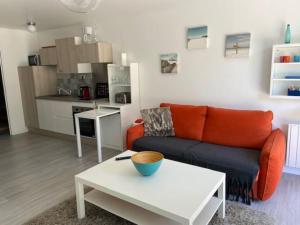 a living room with an orange couch and a table at La Garrigue, au milieu des pins maritimes... in Cucq +12 photos