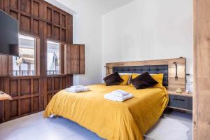 a bedroom with a yellow bed with towels on it at Apartamento exclusivo con vistas únicas en triana in Seville