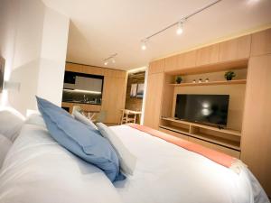 een slaapkamer met een wit bed met blauwe kussens en een tv bij Encantador Depto tipo Studio en Lastarria Servicio HOM in Santiago