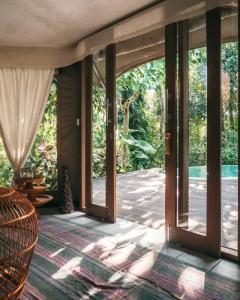 an open glass door to a patio with trees at Sandat Glamping Tents in Ubud