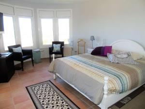a bedroom with a bed and two chairs and windows at Villa avec piscine et vue panoramique mer in Roses