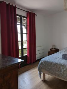 a bedroom with red curtains and a bed and a window at Au chalet d'Illiers Combray, grand jardin arboré in Illiers
