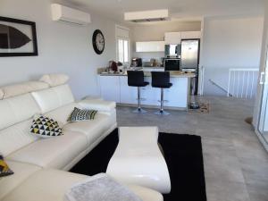 ein Wohnzimmer mit einem weißen Sofa und einer Küche in der Unterkunft Villa avec piscine et vue panoramique mer in Roses