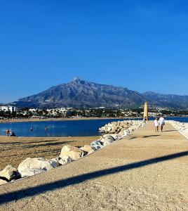 due persone che camminano su una spiaggia vicino all'acqua di Don Paco Modern Loft a Marbella