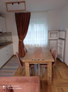 een houten tafel in een keuken met stoelen eromheen bij Apartament Cristina in Borşa