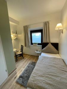a bedroom with a bed and a window and a desk at Landgasthof zur Sonne in Dillingen an der Donau