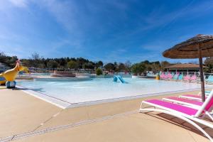 a large swimming pool with chairs and an umbrella at Mobilehome familial in Gastes +11 photos