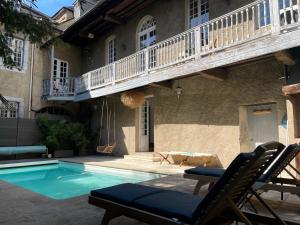 - une piscine en face d'une maison avec balcon dans l'établissement La Maison aux murs anciens et ses chambres, à Tarbes