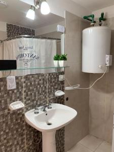 a bathroom with a white sink and a water heater at Apart Ocampo Catamarca in San Fernando del Valle de Catamarca