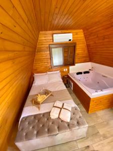 um quarto amplo com uma cama e uma banheira em Chalés da Serra em São Francisco de Paula