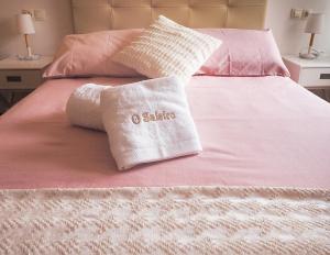 Una cama con sábanas rosas y almohadas. en Apartamento O SALEIRO, en Padrón