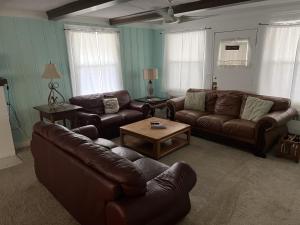 a living room with leather couches and a coffee table at Historic Beach Side Getaway - Pet friendly, WiFi cottage in Norfolk