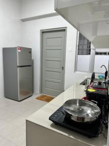 a kitchen with a stove with a pan on the counter at Manjung Vermogen Stay-Wi-Fi+KTV(Near Aeon) in Sitiawan