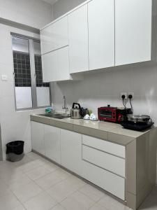 a kitchen with white cabinets and a counter top at Manjung Vermogen Stay-Wi-Fi+KTV(Near Aeon) in Sitiawan