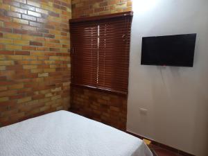 a bedroom with a bed and a flat screen tv at Cabañas GARUTO in Los Santos