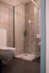a shower with a glass door next to a toilet at Bogentrakt Hostel in Chur +33 photos