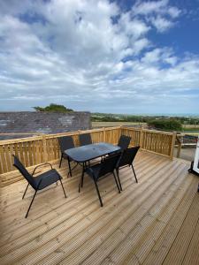 a patio with a table and chairs on a deck at Snowdon Bay - North Wales - Stunning Llyn Peninsula Mountain & Ocean Views in Pwllheli