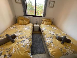 1 dormitorio con 2 camas con sábanas amarillas y ventana en Casa Estrellita - Lovely beachside 3 bedroom duplex flat, en Los Alcázares