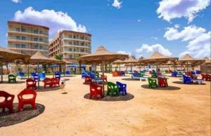 plaży z krzesłami, stołami i parasolami w obiekcie كازابلانكا بيتش w mieście `Ezbet Bûgti