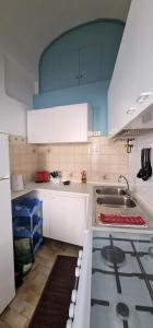 uma cozinha com armários brancos e um forno com placa de fogão em Apartment Martina em Imperia