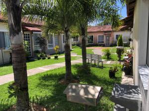 a courtyard with palm trees and benches in front of a building at Casa Exclusiva a 400 Metros da Praia em Manguinhos - Condomínio com Vigilância 24hs in Serra