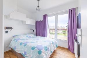 een slaapkamer met een bed en een raam met paarse gordijnen bij Eole - Appt avec vue mer in Saint-Aubin-sur-Mer