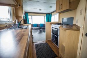 a kitchen with a stove and a sink in a caravan at 6 Berth Caravan Nearby Great Yarmouth In Norfolk Ref 10022rp in Belton