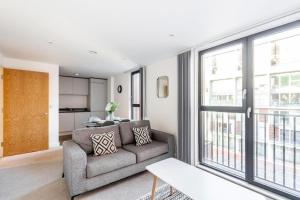 ein Wohnzimmer mit einem Sofa und einem großen Fenster in der Unterkunft Stylish 1 Bedroom Apartment by BOLD Apartments in Liverpool