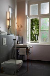 a bathroom with a shower and a toilet and two windows at Wil7 Boutique Hotel in Berlin