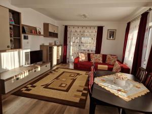 a living room with a table and a red couch at Casă și curte confortabilă in Braşov