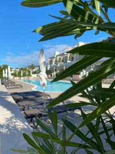 uma vista para uma piscina com cadeiras e um resort em Residence Jesolo Lido centro con piscina em Lido di Jesolo