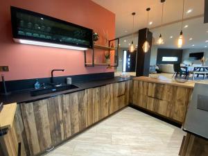 cocina con armarios de madera, fregadero y TV en Villa Giulia, en Montjoie-en-Couserans
