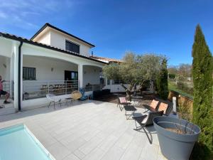 un patio con sillas y una piscina junto a una casa en Villa Giulia, en Montjoie-en-Couserans
