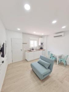 a living room with a blue couch and a kitchen at Gemini Conil in Conil de la Frontera