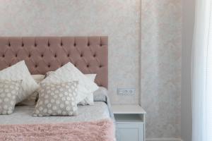um quarto com uma cama com uma cabeceira e almofadas cor-de-rosa em Los Alamos Beach Flat em Torremolinos