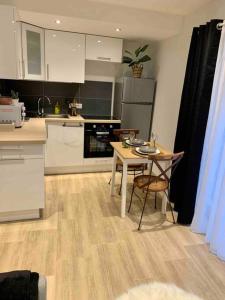 une cuisine avec des armoires blanches et une table et des chaises dans l'établissement Studio cosy Kaysersberg centre, à Kaysersberg