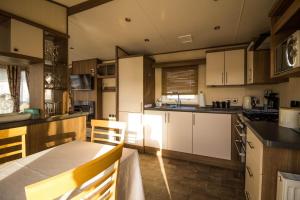uma cozinha com armários brancos e uma mesa em Lovely Caravan With Decking At Breydon Water In Norfolk Ref 10003b em Belton
