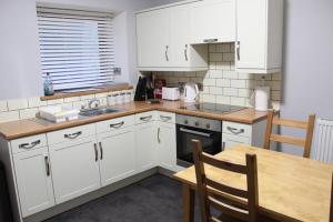 een keuken met witte kasten en een houten tafel bij Newly Refurbished 2 Bedroom flat on NC500 route in Wick