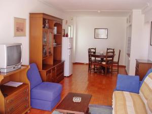 a living room with a couch and a tv at Apartamentos Salema Praia Club in Salema