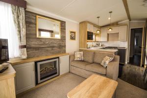 ein Wohnzimmer mit einem Sofa und einem Kamin in der Unterkunft Modern Caravan At Caldecott Hall With Decking In Norfolk, Sleeps 8 Ref 91068c in Great Yarmouth