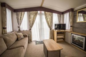 a living room with a couch and a tv at Modern Caravan At Caldecott Hall With Decking In Norfolk, Sleeps 8 Ref 91068c in Great Yarmouth