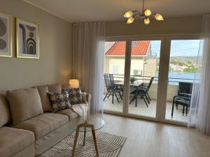 a living room with a couch and a table and a balcony at Luxury Old Town Apartment with Sea View in Rogoznica