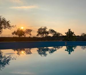 a pool with the sunset in the background at Villa delle Stelle in Cassaro