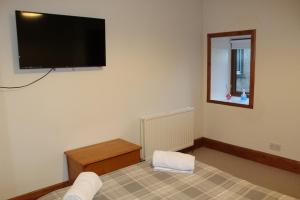 a room with a tv on the wall and a bed at Newly Refurbished 2 Bedroom flat on NC500 route in Wick