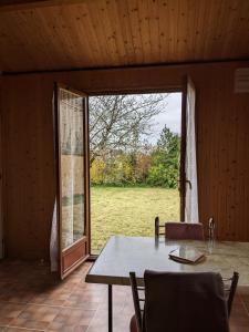 ein Esszimmer mit einem Tisch und einer großen Glasschiebetür in der Unterkunft Au petit chalet d'Illiers Combray in Illiers