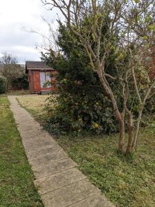 a sidewalk in a yard with a tree and a house at Au petit chalet d'Illiers Combray in Illiers
